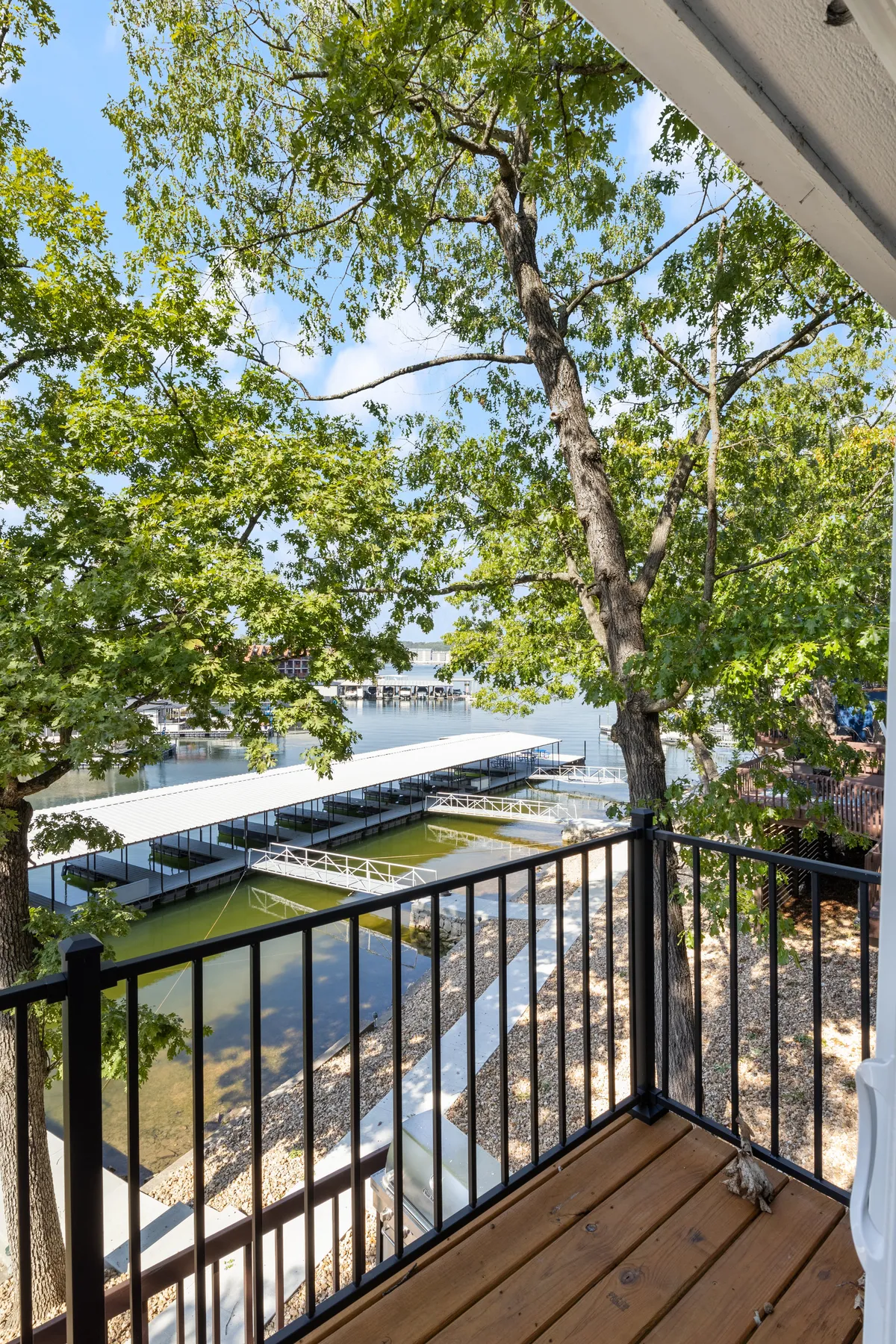 A tranquil exterior view showcases the sparkling lake, surrounding docks, and lush trees, all bathed in the warm hues of sunset. The vantage point hints at opportunities for waterside relaxation and gathering, with the calm water reflecting the sky above.
