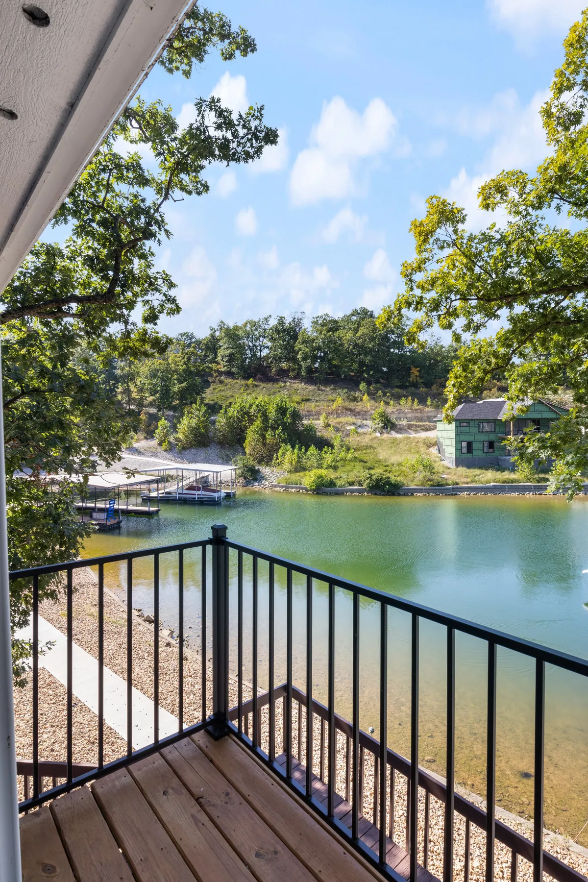 This image reveals a tranquil lake, calm waters reflecting soft light, docks extending into the water, and trees framing the scene. The composition suggests a peaceful, private cove ideal for lakeside relaxation, morning coffee, or quiet moments together.