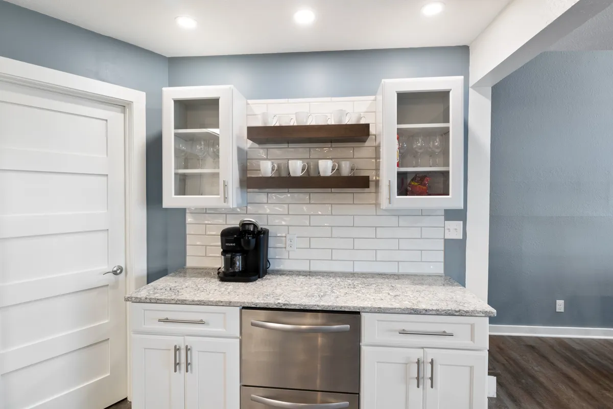 A cozy kitchen corner with a granite countertop, a coffee maker, glass dishware, and open shelving. The setup suggests the possibility of enjoying morning coffee while overlooking serene views, echoing the section’s emphasis on starting the day in comfort.